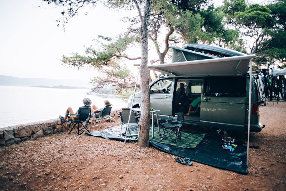 camper van with awning overlooking a lake
